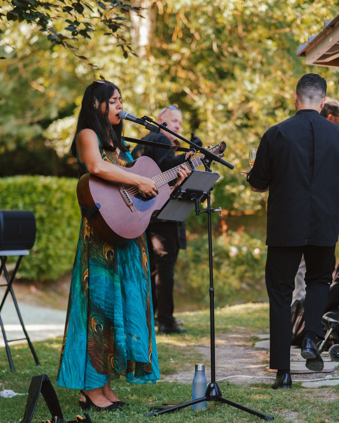 Sumana singing at an outdoor company event, guests standing