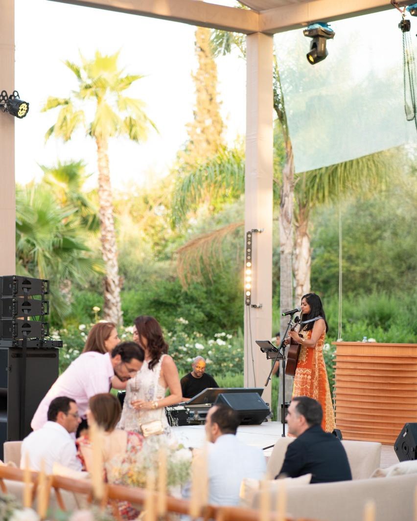 Sumana singing at an outdoor corporate dinner, guests seated