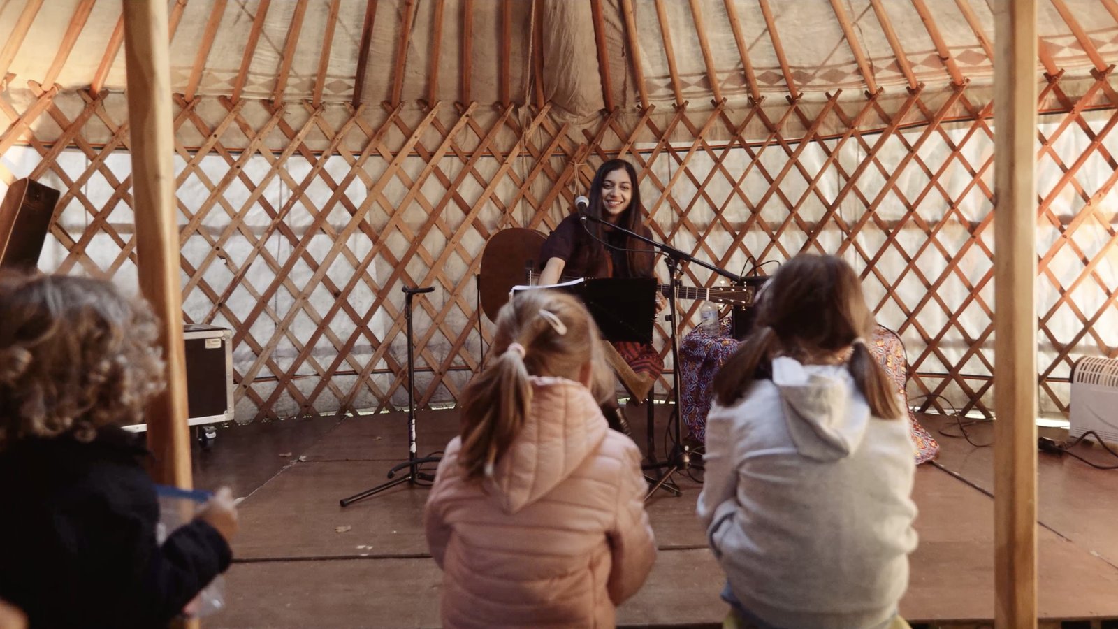 Sumana playing guitar for children in a yurt